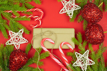 Christmas composition. Gifts, spruce branches, red shiny decorations on a red background. 