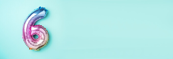 Creative layout. Rainbow foil balloon number and digit six 6. Birthday greeting card. Anniversary concept. Top view. Copy space. Stylish colored numeral over blue background. Numerical digit.