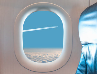 Naklejka premium Trail of white smoke from the airplane on blue sky as seen through window of an aircraft