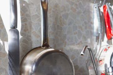 Steel utensils hang on the railing in the kitchen of the house.