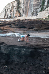 young woman practicing exercise on the beach during sunset