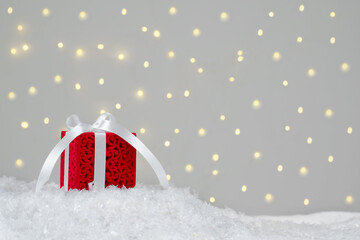 Red gift on white snow. Background with bokeh
