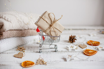 Fototapeta na wymiar Christmas shopping cart for supermarket with a gift on a wooden background