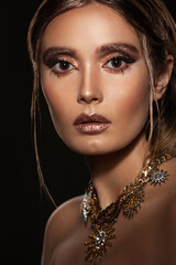 portrait of a beautiful girl with skillful makeup and jewelry on a dark background
