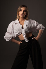 beautiful girl in wide pants and a white shirt on a dark background