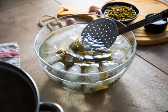 bol con hielo y verduras verdes saludables reci&eacute;n cocinadas sobre la mesa de la cocina