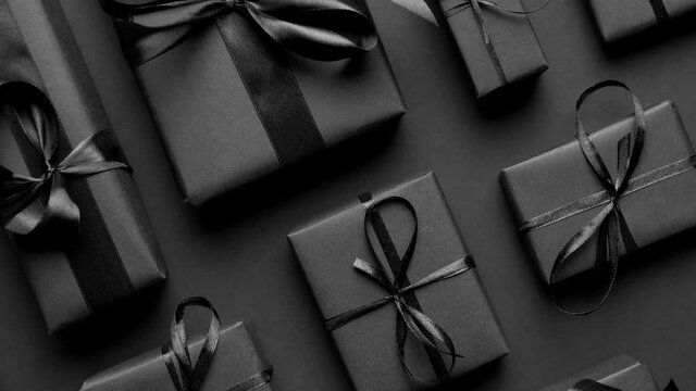Dark Christmas theme. Square boxed gifts wrapped in black paper and ribbon arranged on black