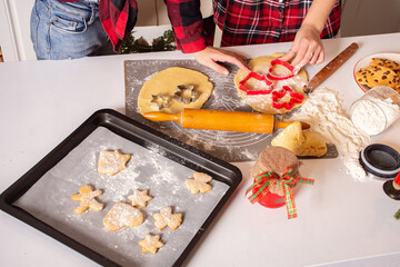 Christmas cookies. Kitchen on Christmas eve. Hands of mother and children roll out the dough and form Christmas cookies.