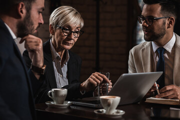 Senior businesswoman holding a meeting with her younger colleagues at office cafeteria.