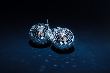 two mirror balls illuminated by bright light lie on dark blue background with reflections