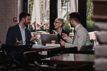 Senior businesswoman holding a meeting with her younger colleagues at office cafeteria.