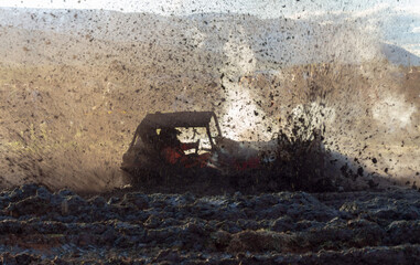 Buggy like car driving into a wet and muddy road splashing mud everywhere