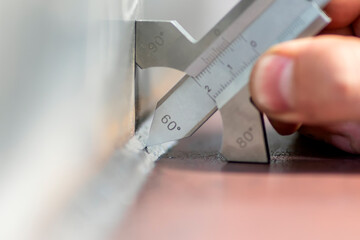 The inspector is measuring to fillet weld thickness with welding caliper (gauge).