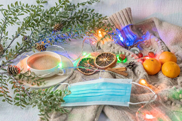 Medical mask and accessories for the New Year, green twig, dry oranges, Czech woman with coffee, Christmas tree garland, woolen sweater. Flatley on white background. Concept of congratulation merry ch