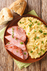 pease pudding is made from cooking yellow split peas served with fried ham closeup in the plate on the table. Vertical top view from above