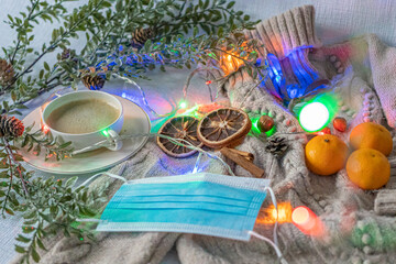 Medical mask and accessories for the New Year, green twig, dry oranges, Czech woman with coffee, Christmas tree garland, woolen sweater. Flatley on white background. Concept of congratulation merry ch