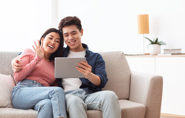 Chinese Couple Making Video Call Via Digital Tablet At Home