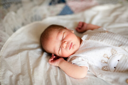 Newborn baby boy in bed. New born child in white bodykit lying in light cradle. Children sleep. Bedding for kids. Infant napping in bed. Healthy little kid shortly after birth