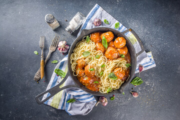 Homemade spaghetti pasta with meatballs in tomato sauce, dark concrete background above