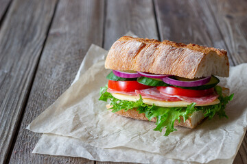Sandwich with sausage, cheese, green salad, tomatoes, cucumbers and onions. Fast food. Breakfast. Healthy eating.