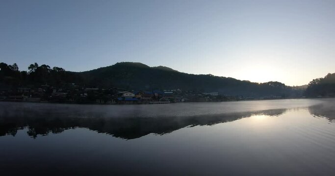 Time lapse during dawn to sunrise over the lake with fog floating on the water surface at "Ban Rak Thai village" a Village is travel destination in Mae Hong Son, Thailand.