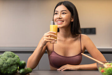 Woman Drinking Juice Losing Weight On Diet Sitting In Kitchen
