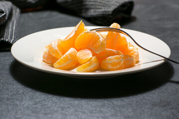 peeled oranges in pieces on a plate with fork