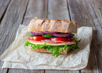 Sandwich with sausage, cheese, green salad, tomatoes, cucumbers and onions. Fast food. Breakfast. Healthy eating.
