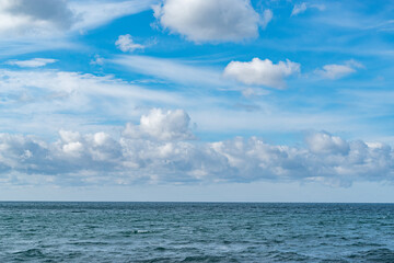 Fototapeta na wymiar 青空に浮かぶ雲とエメラルドグリーンの海の地平線