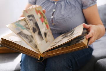 woman looking through an album with old photographs, concept of memories of youth, childhood,...