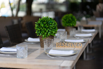 The plaque is reserved on the served table of a summer outdoor cafe or restaurant. Shallow depth of field, blurred background