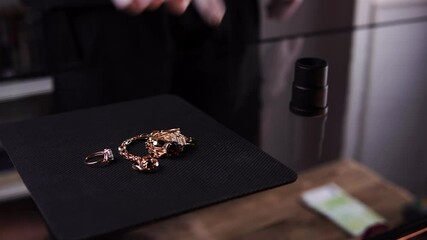 A woman brought gold rings and chainlets to a pawn shop for selling in close-up. An owner is appraising jewelry and paying cash to a lady. A man takes away all bijou Concept of buying precious metals.