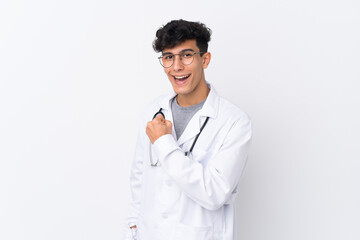 Young Argentinian man over isolated white background wearing a doctor gown and making victory gesture