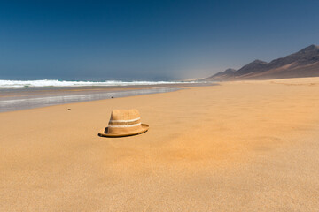 Fototapeta na wymiar Hat on the virgin beaches on the island of Fuerteventura. Cofete beach on the island of Fuerteventura, Spain
