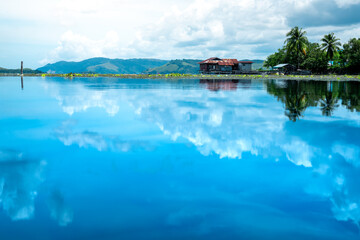 Fototapeta na wymiar A quiet view of the lake with a reflection of the blue sky on the surface of the water. Beautiful lake landscape photos for backgrounds and wallpapers