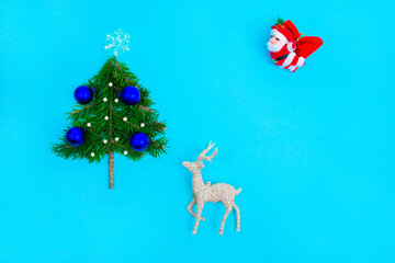 Small Christmas tree decorated with blue balls on turquoise background. Holiday greeting card.