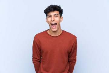 Young Argentinian man over isolated blue background with surprise facial expression