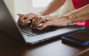 senior reitred woman typing on keyboard of computer at home