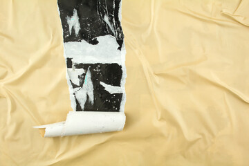 Torn and peeling beige poster glued on billboard with old dirty paper. Abstract and creative...