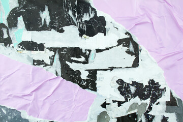 Torn black and purple posters glued on billboard with old dirty peeling paper. Abstract and...