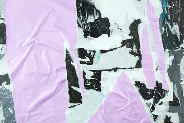 Torn and crumpled purple poster glued on billboard with old dirty paper. Abstract and creative background of ripped magazine paper.