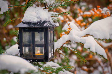 Black lantern with candle hanging from Fir tree