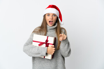 Lithianian woman with christmas hat holding presents isolated on white background surprised and pointing front