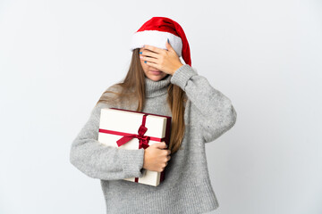 Lithianian woman with christmas hat holding presents isolated on white background covering eyes by hands. Do not want to see something