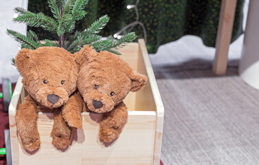 Two teddy bears in a wooden box with a Christmas tree.