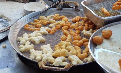 A large number of patongo are being fried in the pan. At street food stalls.