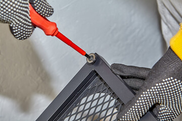 Tightening screws in door hinges of flat pack shelf by handyman.