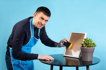 A man wipes the mirror and looks at the camera.Blue background.Gender stereotype