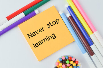 Selective focus of pen colors, pinboards and memo note written with text NEVER STOP LEARNING. Education concept. 