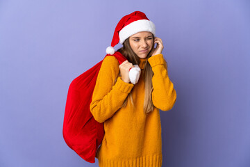 Lithianian woman with christmas hat isolated on purple background frustrated and covering ears